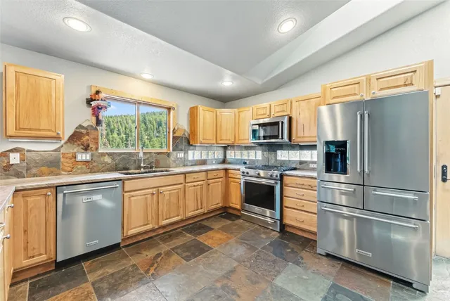 a kitchen with stainless steel appliances granite countertop a refrigerator and a stove top oven