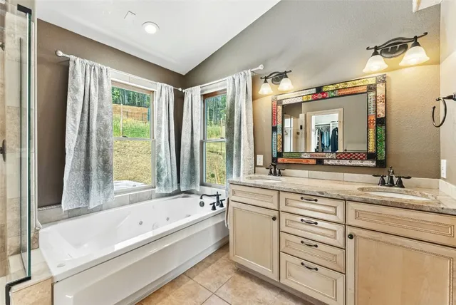 a bathroom with a bathtub a double vanity sink and mirror