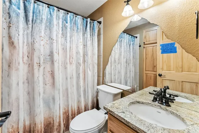 a bathroom with a granite countertop sink toilet and shower