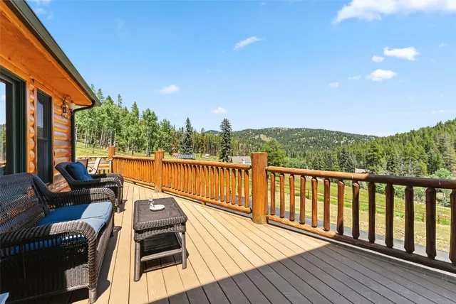 a balcony with wooden floor and trees in the back