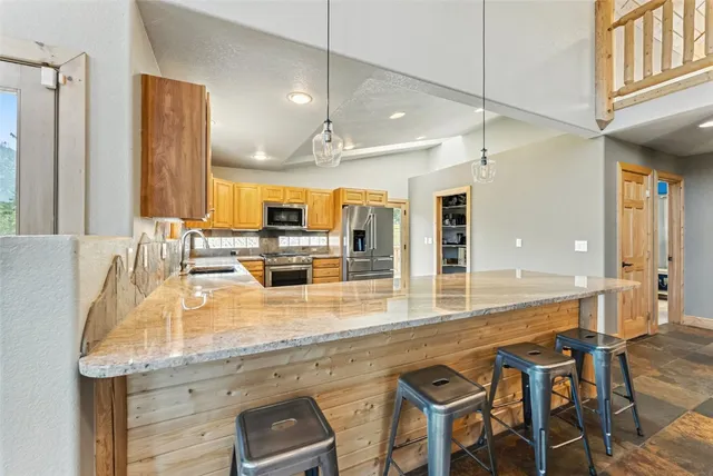 a dining hall with stainless steel appliances kitchen island granite countertop a table chairs and a refrigerator