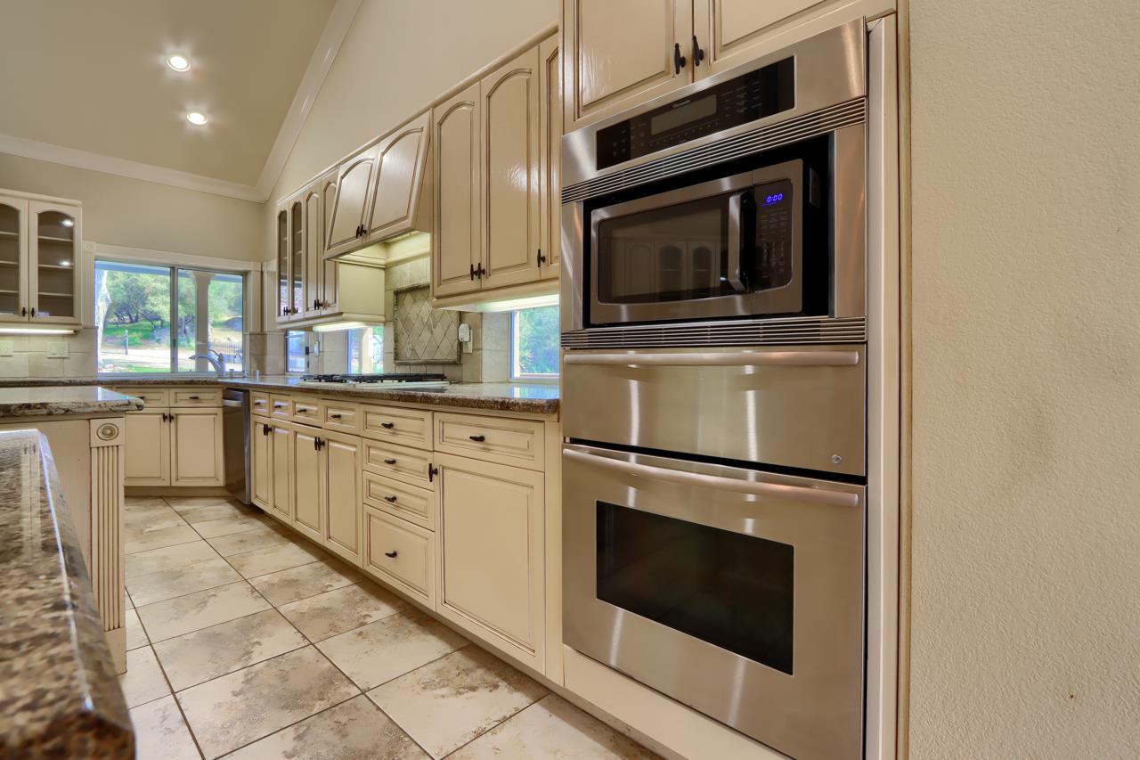 46580 Vista Del Rio Drive Oakhurst, CA 93644 - Photo 16 of 82 a kitchen with granite countertop white cabinets stainless steel appliances and sink