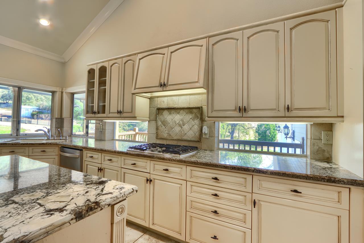46580 Vista Del Rio Drive Oakhurst, CA 93644 - Photo 17 of 82 a kitchen with granite countertop white cabinets and white appliances