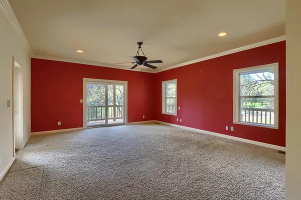 an empty room with a window and a chandelier fan