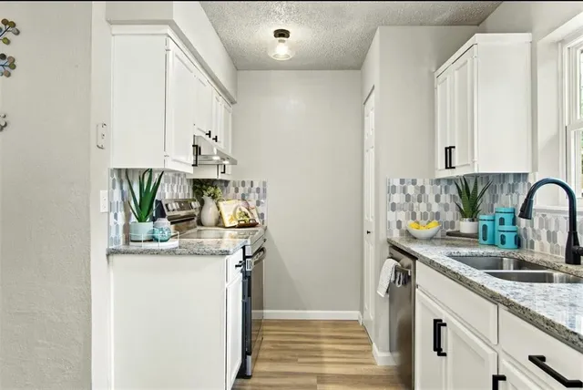 a kitchen with stainless steel appliances granite countertop a sink a stove and a refrigerator