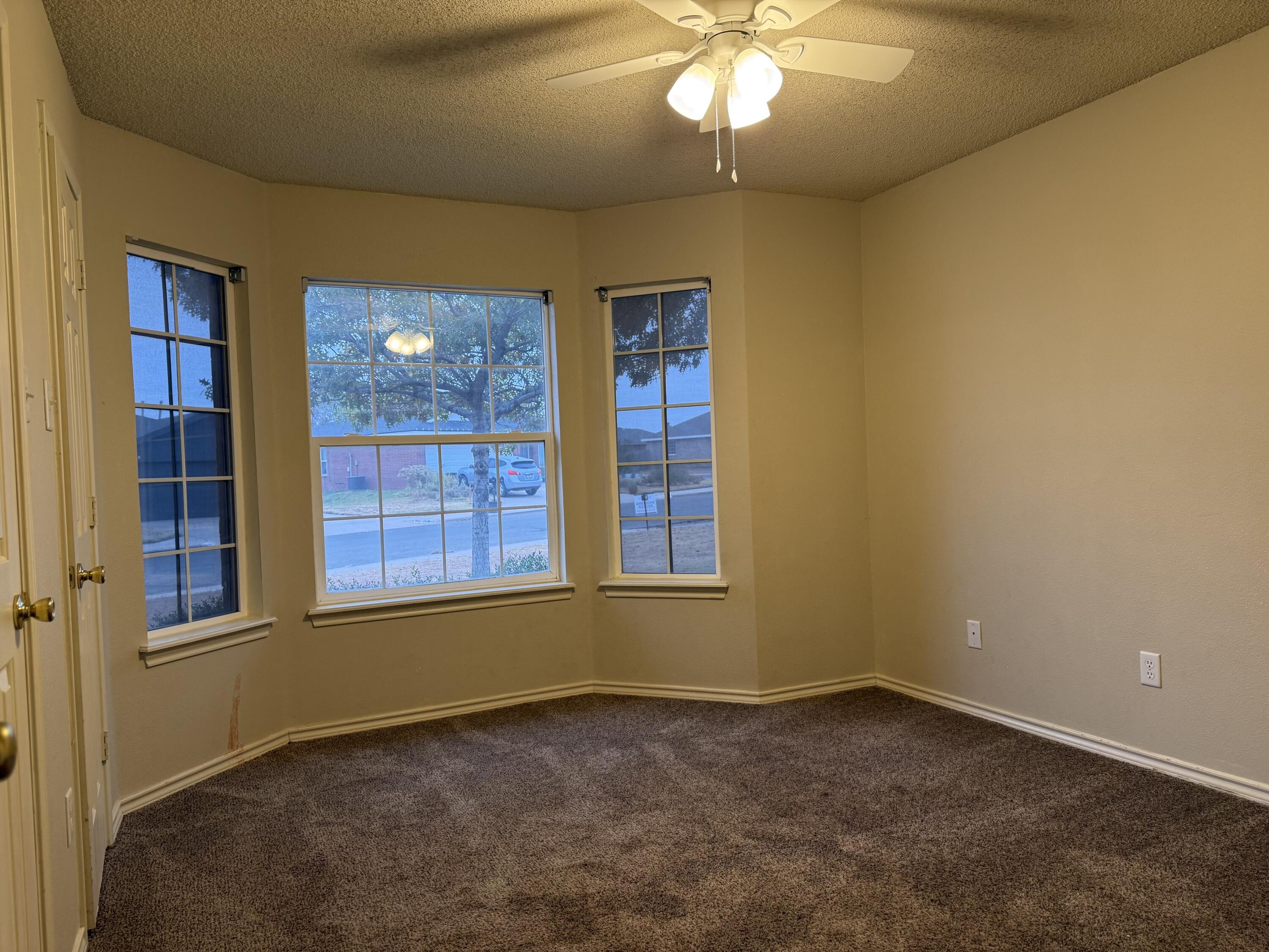 10602 Akron Avenue Lubbock, TX 79423 - Photo 11 of 16 an empty room with a chandelier fan and windows