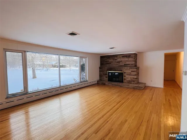 a view of empty room with wooden floor and fireplace