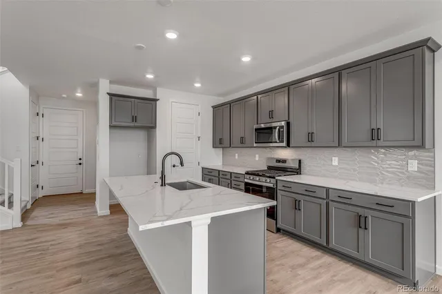 a kitchen with stainless steel appliances granite countertop a sink stove and refrigerator