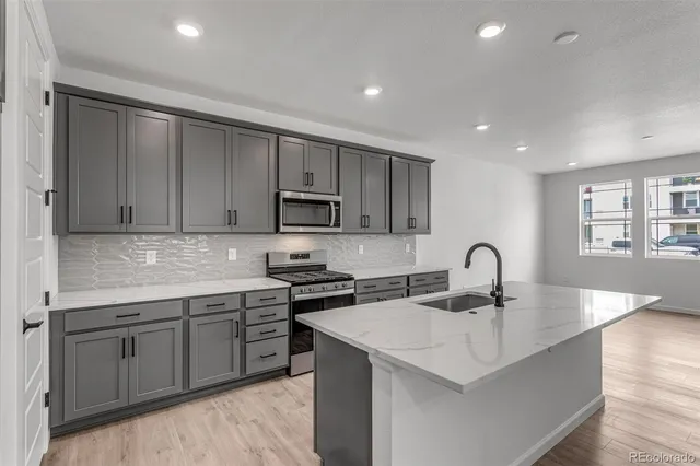 a kitchen with stainless steel appliances a sink a stove a microwave a center island and cabinets