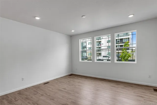 an empty room with wooden floor and windows