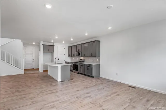 a large kitchen with a large counter top a sink stainless steel appliances and cabinets