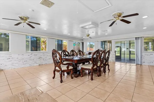 a view of a dining room and livingroom with furniture wooden floor a rug a painting and a chandelier