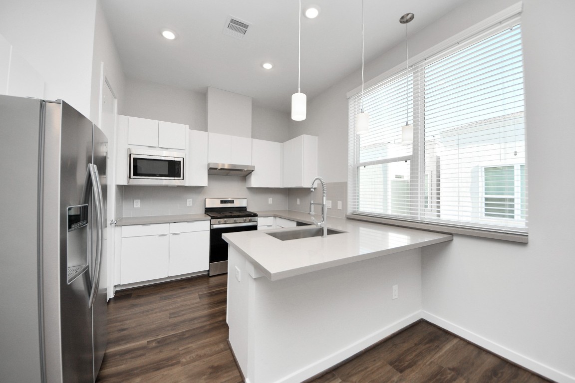 608 Thornton Road, Unit A Houston, TX 77018 - Photo 29 of 44 a kitchen with a sink a microwave a stove and refrigerator