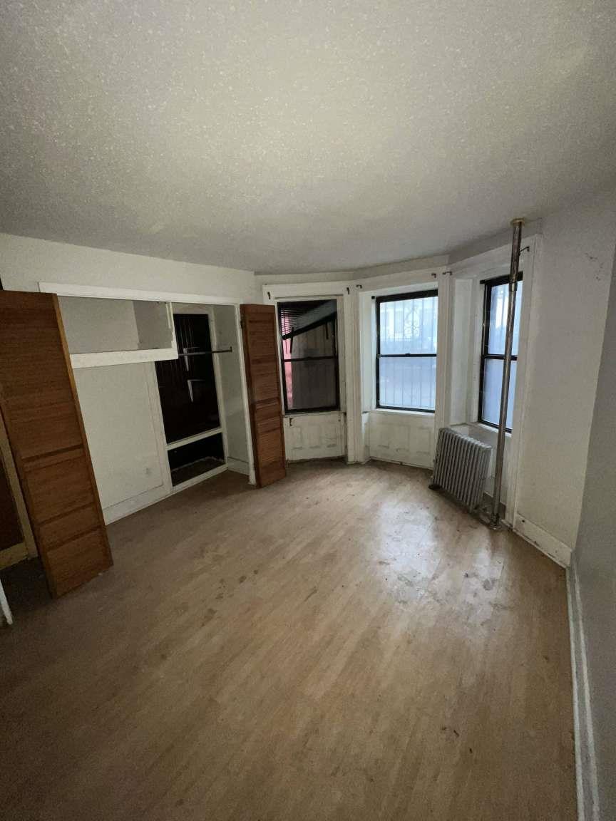 1430 Pacific Street Brooklyn, NY 11216 - Photo 7 of 24 Unfurnished bedroom featuring radiator, light hardwood / wood-style floors, and a textured ceiling