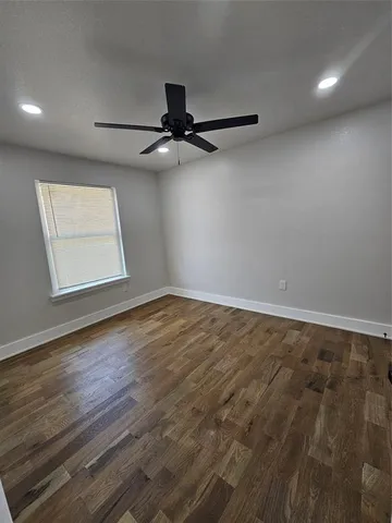 an empty room with wooden floor ceiling fan and windows