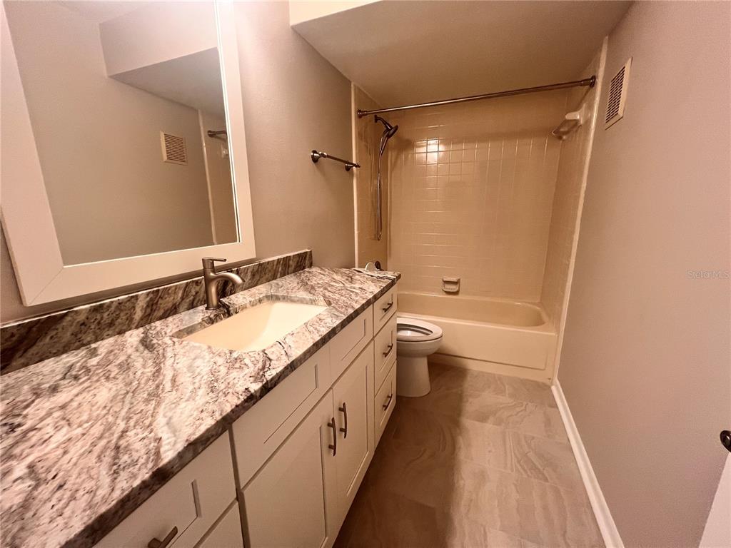 17 Escondido Circle, Unit 239 Altamonte Springs, FL 32701 - Photo 22 of 30 a bathroom with a granite countertop sink a toilet a mirror and shower