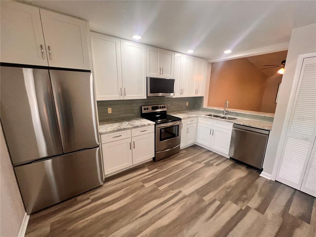 17 Escondido Circle, Unit 239 Altamonte Springs, FL 32701 - Photo 5 of 30 a kitchen with white cabinets stainless steel appliances and a sink