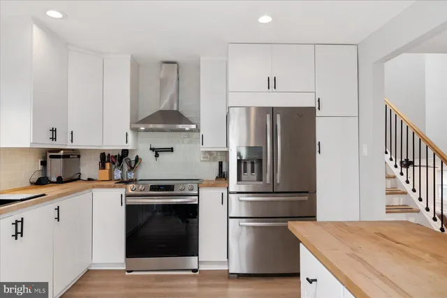 a kitchen with cabinets stainless steel appliances and wooden floor