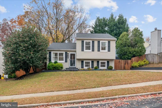 a view of a white house next to a yard with plants and trees