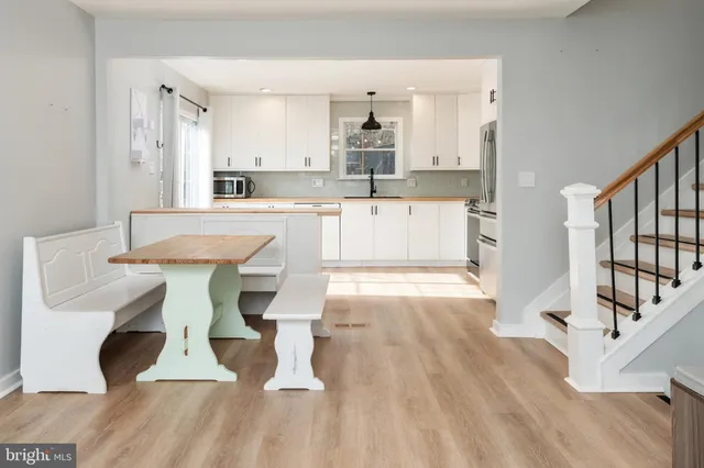 a large white kitchen with wooden floor and stainless steel appliances