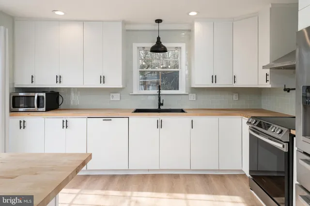 a kitchen with granite countertop a stove a sink and a microwave