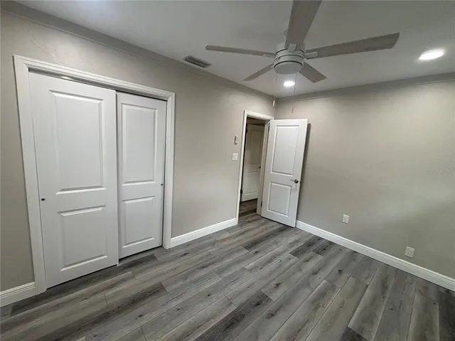 an empty room with wooden floor and a ceiling fan