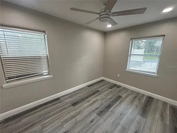 a view of empty room with wooden floor and fan