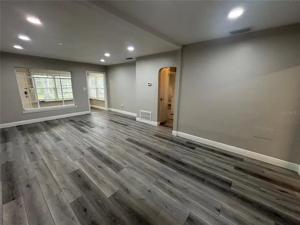 an empty room with wooden floor and windows
