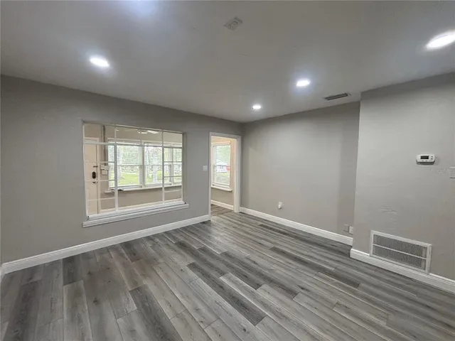an empty room with wooden floor and windows