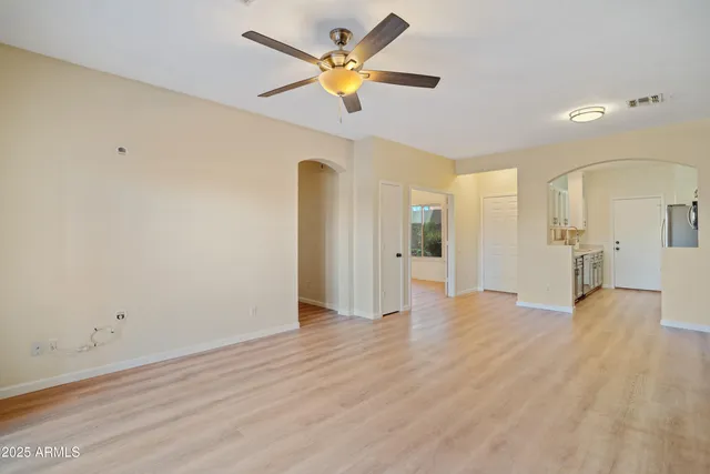 a view of an empty room with window and wooden floor