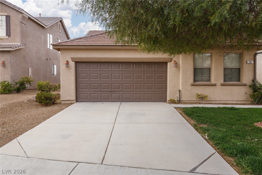 A well-maintained stucco facade with a large concrete driveway provides convenient parking.
