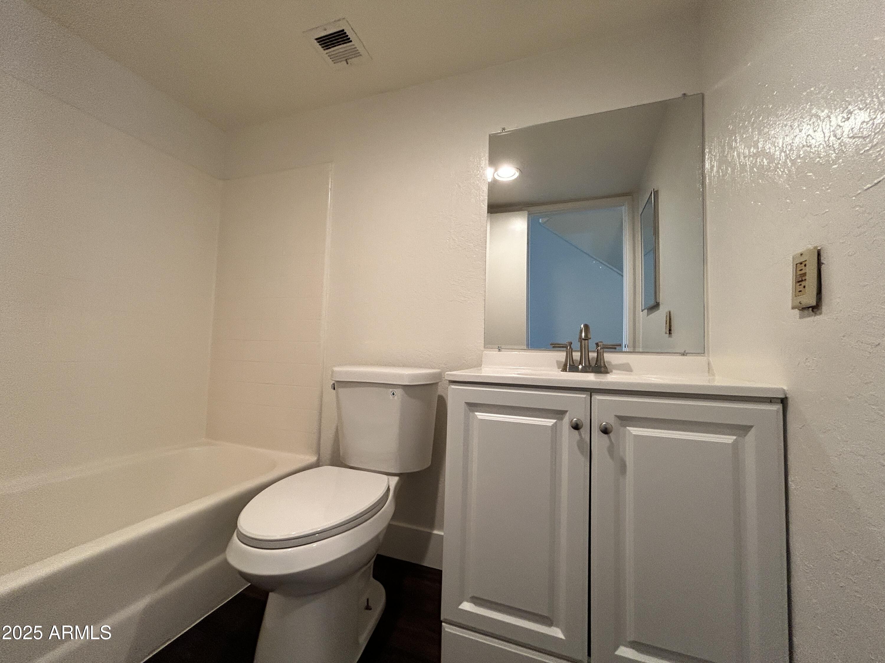1702 East Ocotillo Road, Unit 2 Phoenix, AZ 85016 - Photo 8 of 18 a bathroom with a toilet a sink a mirror a bathtub and vanity