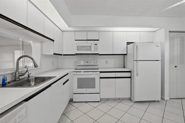 a kitchen with white cabinets and white appliances