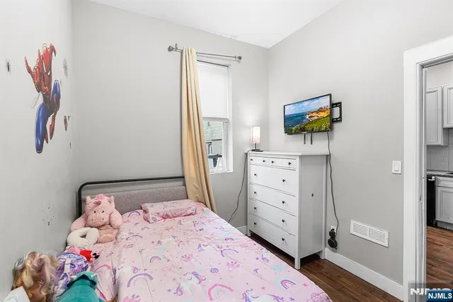 a bedroom with a bed and a flat tv screen on dresser