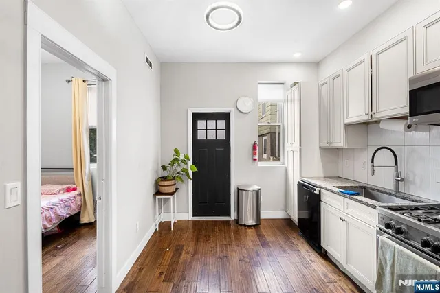 a view of kitchen with stainless steel appliances wooden floor and cabinets