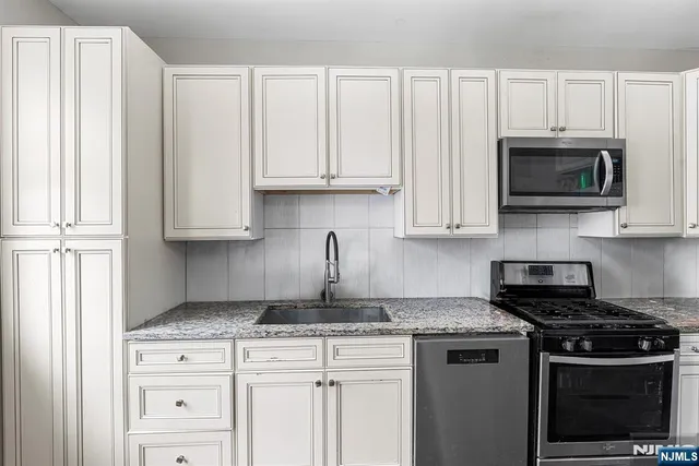 a kitchen with granite countertop white cabinets and black appliances