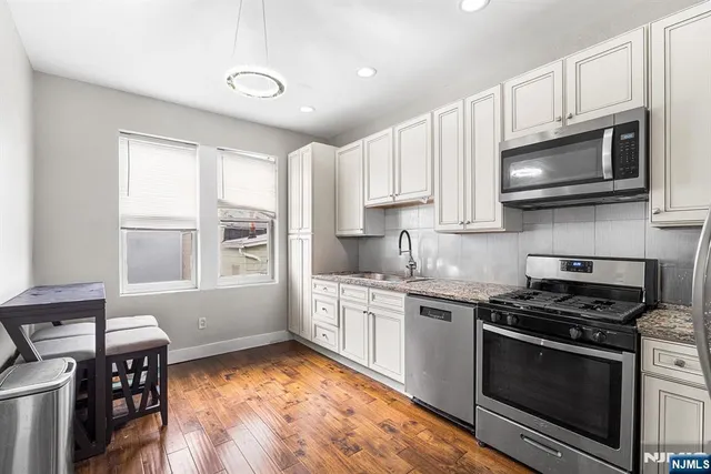 a kitchen with stainless steel appliances granite countertop a stove microwave and sink