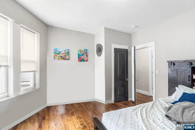 a bedroom with a bed and a window with wooden floor