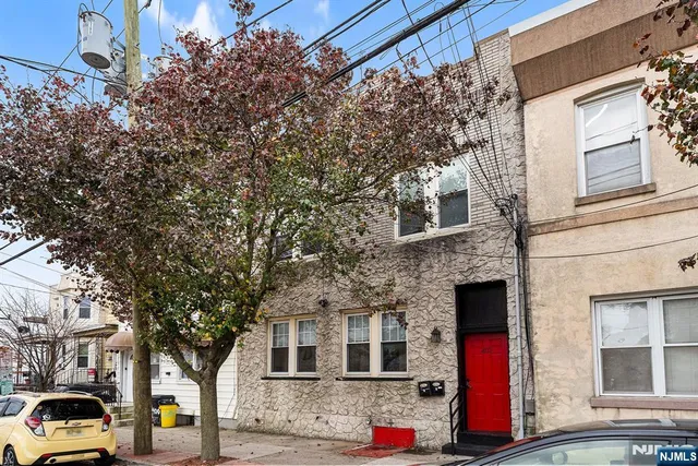 a front view of a building with large trees
