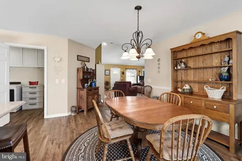 a dining room with furniture a chandelier and kitchen view
