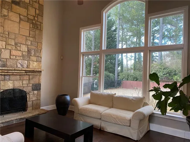 a living room with furniture a fireplace and a floor to ceiling window