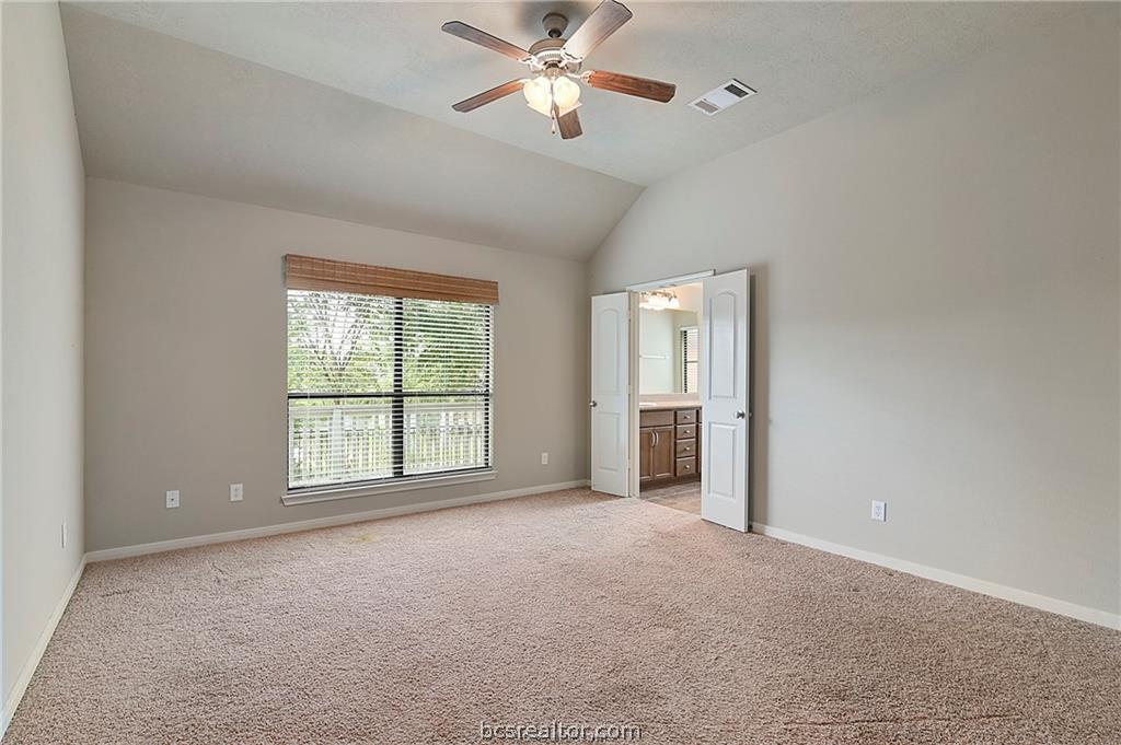 2004 Spring Leaf Court Bryan, TX 77807 - Photo 6 of 19 Unfurnished bedroom with visible vents, baseboards, connected bathroom, lofted ceiling, and light colored carpet