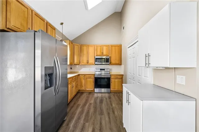 a kitchen with a refrigerator a stove top oven a sink and dishwasher with wooden floor