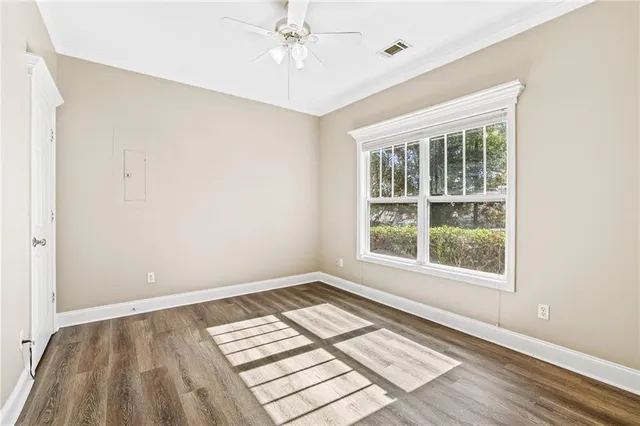 an empty room with wooden floor and windows