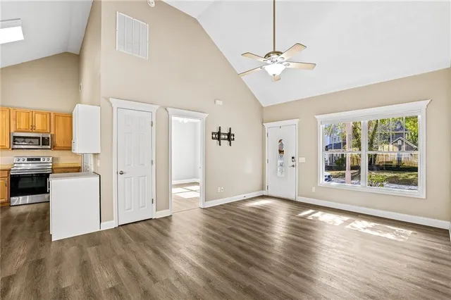 a view of a livingroom with wooden floor a ceiling fan and windows