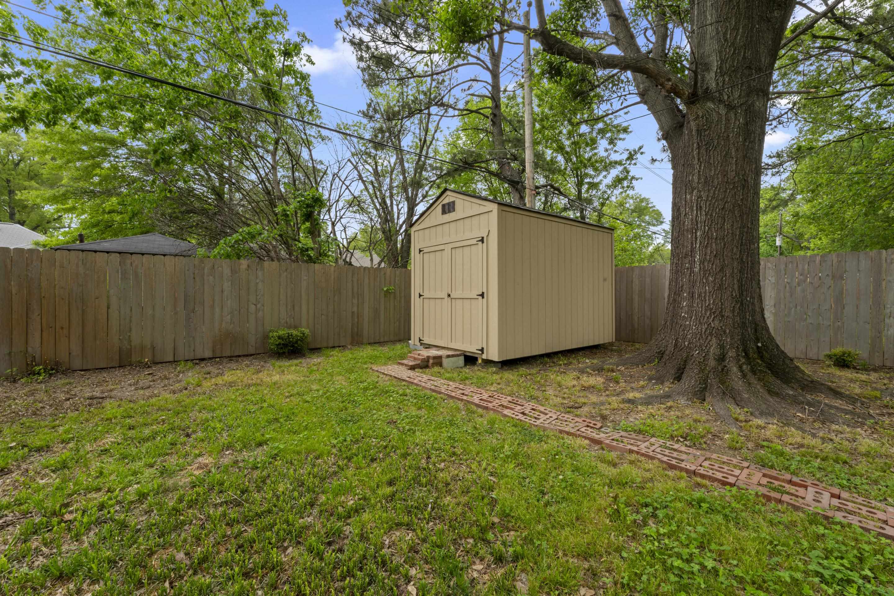 1343 Dearing Road Memphis, TN 38117 - Photo 19 of 19 Spacious backyard featuring a new outdoor shed, mature trees, and a wooden privacy fence