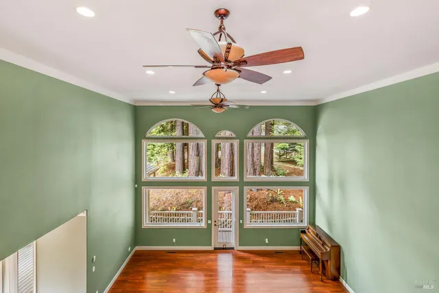 a view of empty room with wooden floor and fan