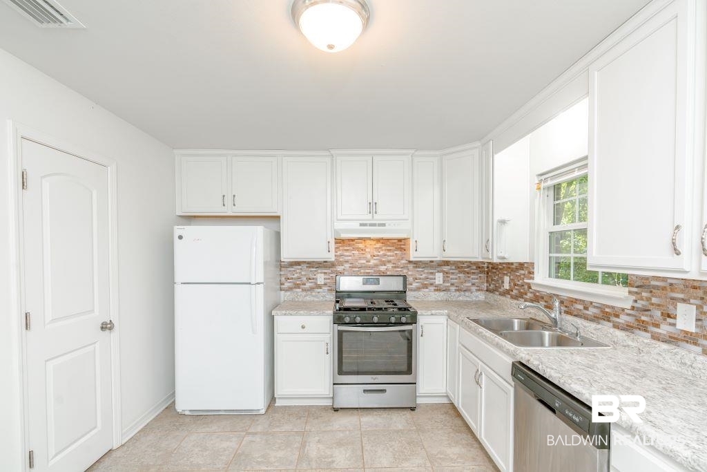 12641 Pecan Street Grand Bay, AL 36541 - Photo 10 of 23 Kitchen with white cabinetry, stainless steel appliances, backsplash, and sink