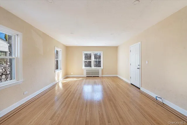 a view of an empty room with wooden floor and windows