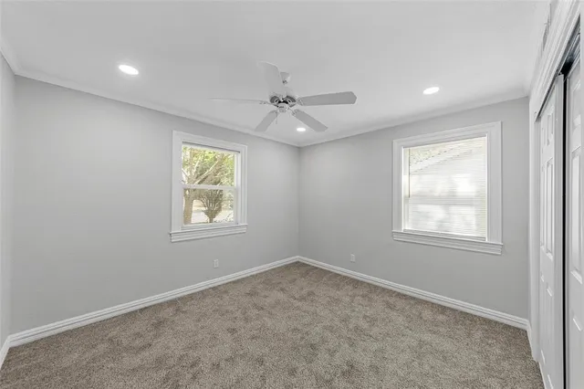 an empty room with a ceiling fan and carpet